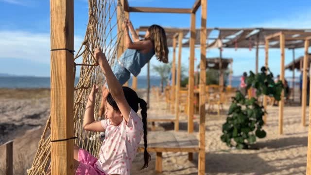 Niños jugando en la estructura de cuerdas frente al mar en Casual